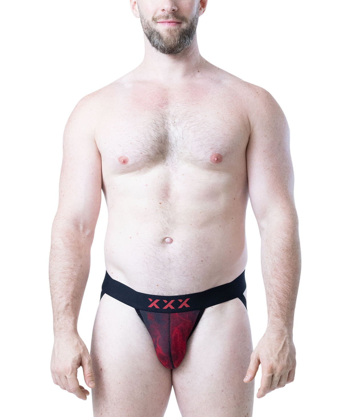 A man modeling a men's jockstrap with a black waistband featuring red XXX lettering, and a red and black marbled fabric pouch, against a solid white background.  The brand is Nasty Pig.