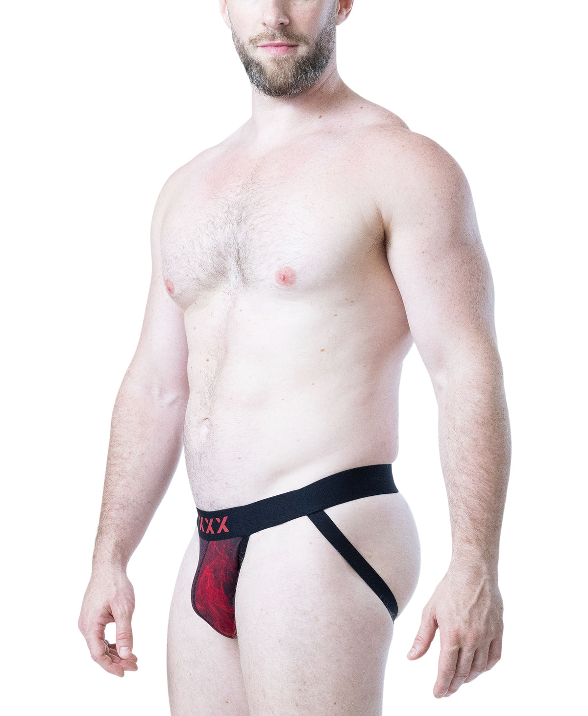 A man modeling a men's jockstrap with a black waistband and leg strap, featuring a red and black patterned pouch, on a solid white background.
