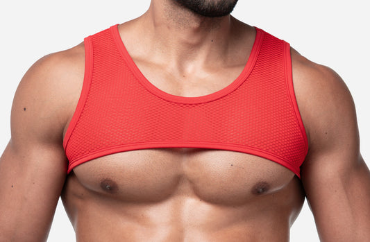 A close-up of a man's chest wearing a bright red athletic tank top harness from PUMP with a textured, breathable mesh-like fabric.